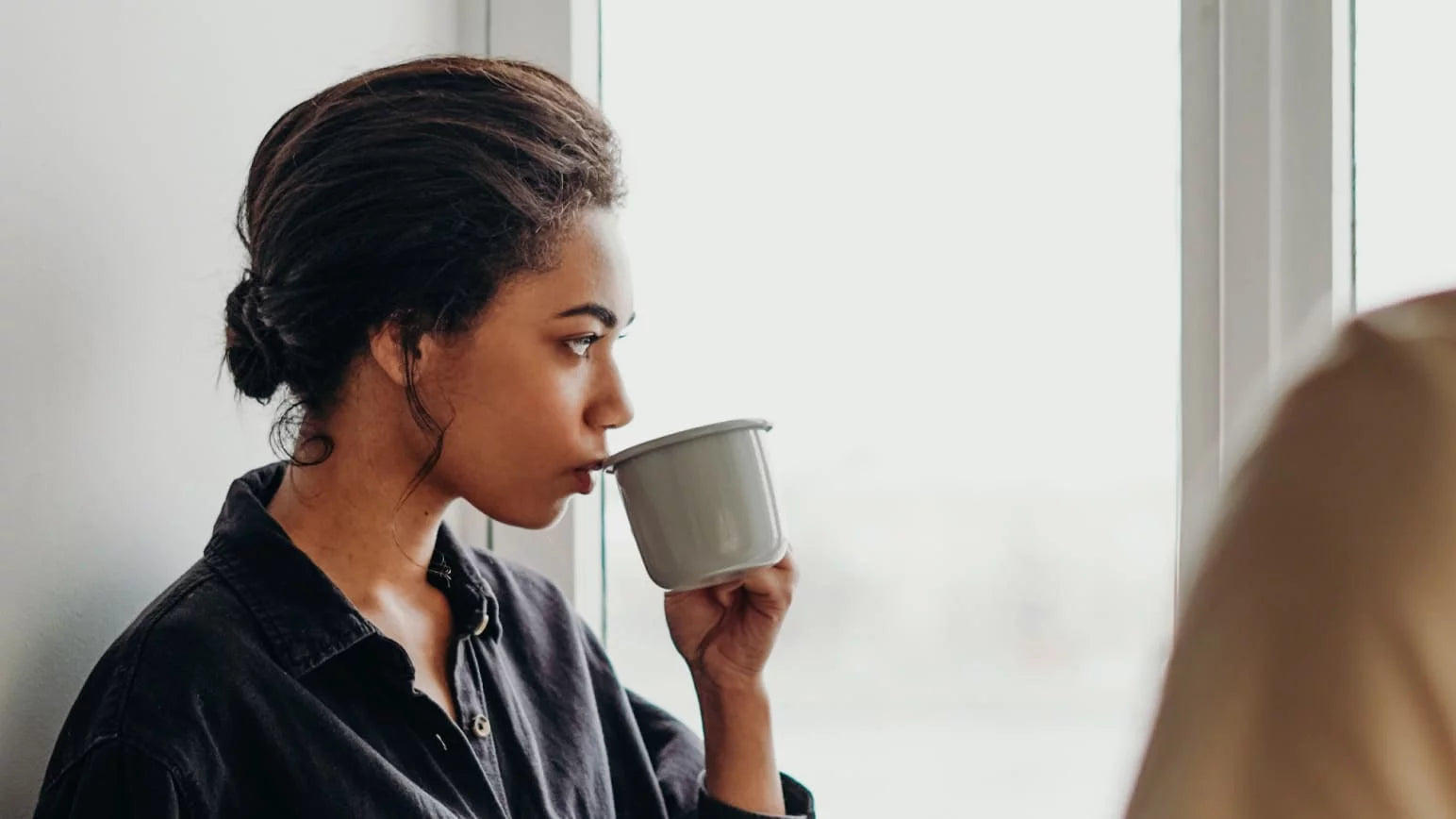 Una mujer tomando una taza con agua y colágeno