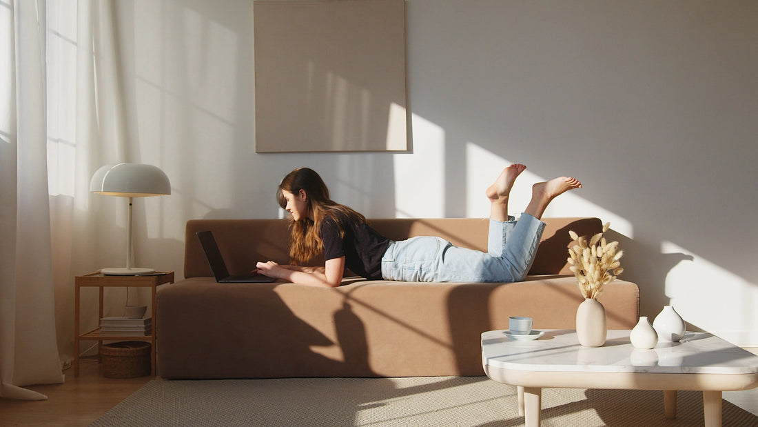 mujer tumbada en el sofa tranajando en el portatil